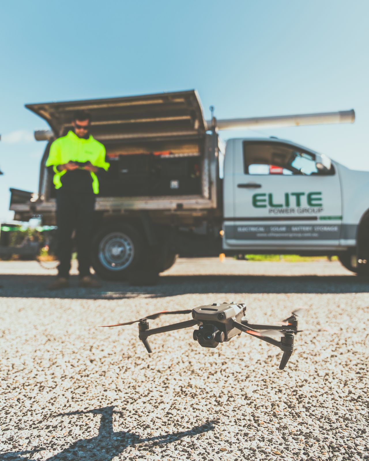 A technician preparing a drone for flight beside a utility truck