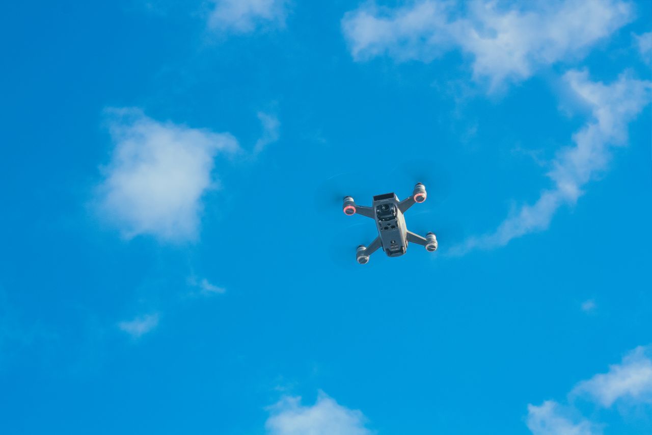 An unmanned aircraft with spinning propellers against a blue sky